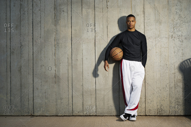 A man leans against a wall with a basketball