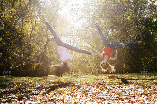 Two young women flip upside-down outside