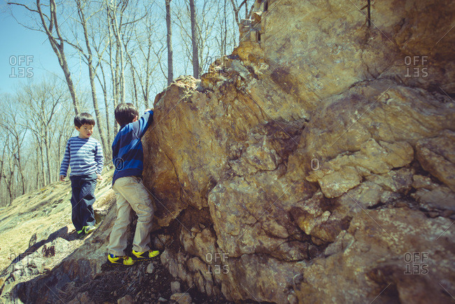 Two boys climbing a rocky rural hill