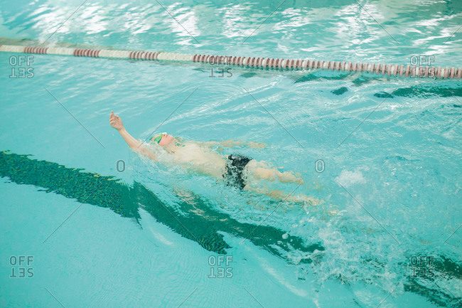 Boy swimming backstroke in pool