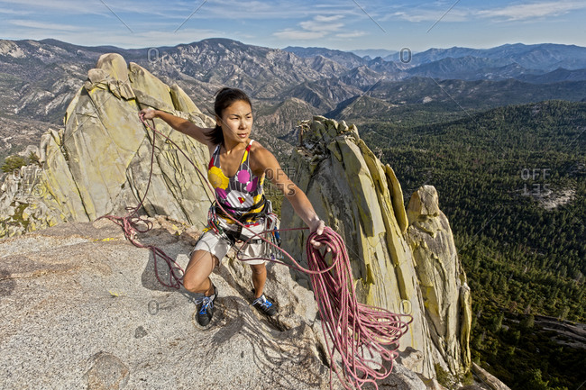 A climber coiling ropes on the summit of a steep rock spire at Joshua Tree National Park