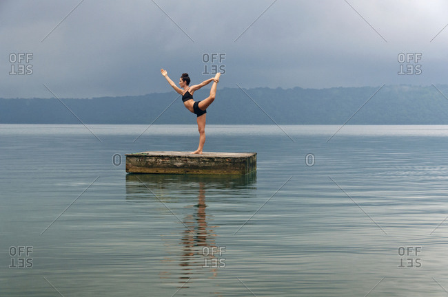 Woman doing yoga on a dock in a lake