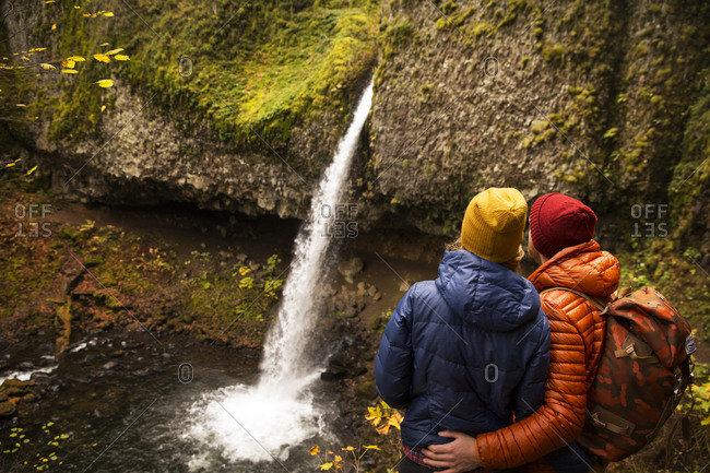 Couple looking at waterfall with arms around each other