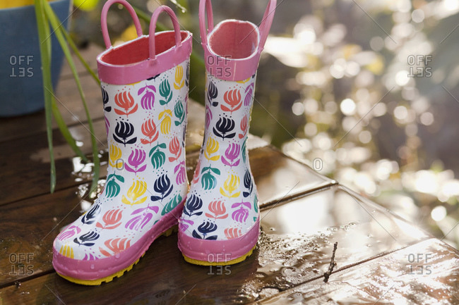 A pair of rain boots dries on a porch