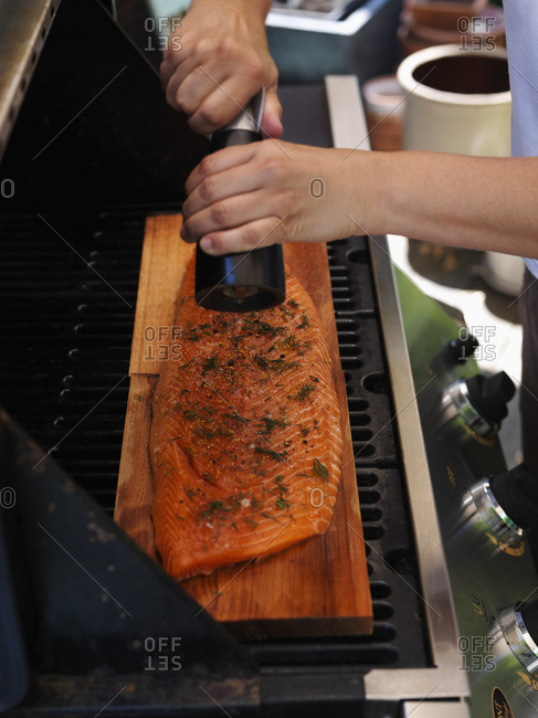 Person grinding pepper onto a salmon