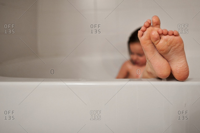 Girl sitting in bathtub with her feet hanging out