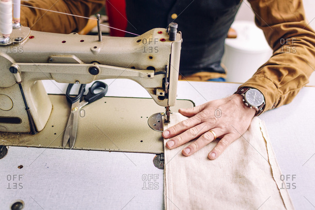 A man sewing a hem at a sewing machine