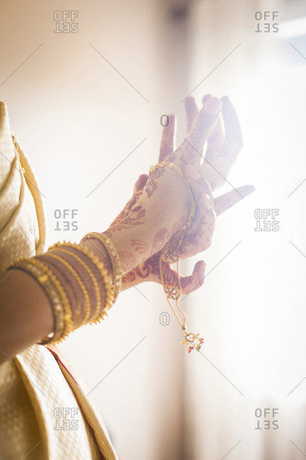 Close up of South Asian bride putting on bangles in front of window