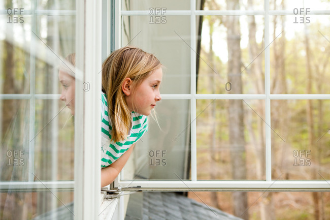 A girl looks out of a window at her house