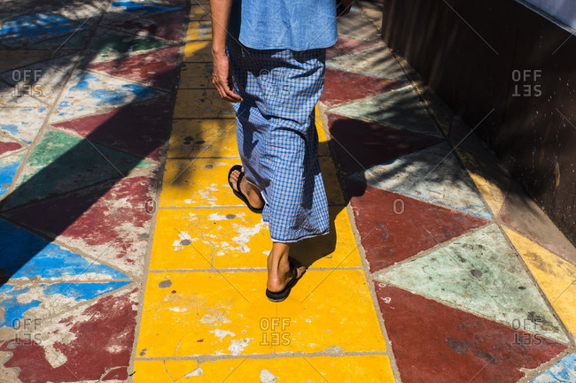 A young Burmese man walks along a yellow foot path in downtown Yangon, Myanmar