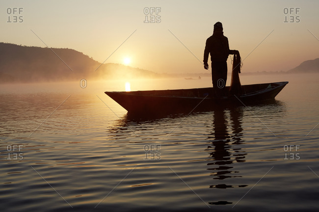 A fisherman on a small canoe on a lake in Pokhara, Nepal