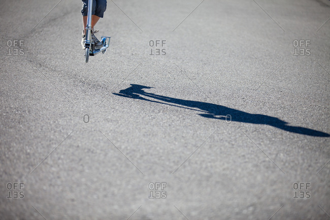 Shadow of a child jumping on a scooter