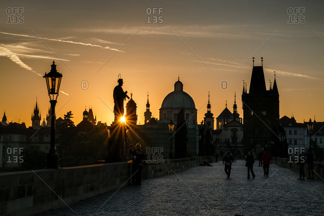 Starburst on silhouetted statue on Charles Bridge from low setting sun, Prague, Czech Republic