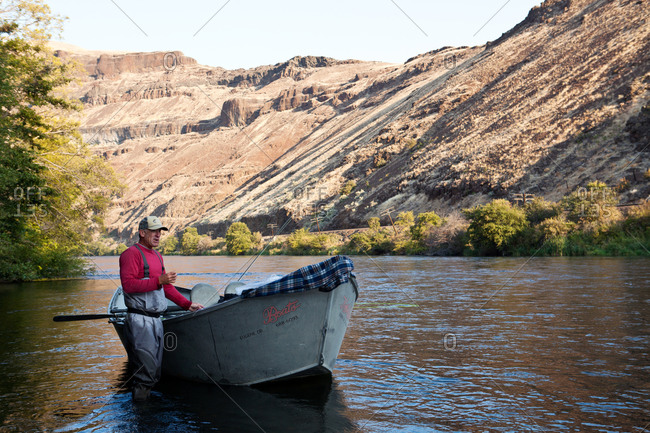 A fisherman walks his boat into a river