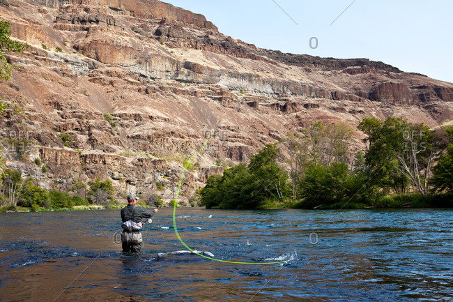 A man casts off in a canyon river