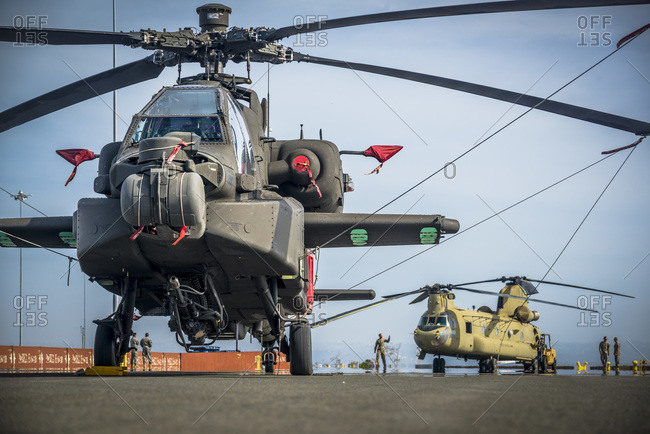 US Army Apache and Chinook Helicopters tied down and awaiting to be loaded aboard a ship