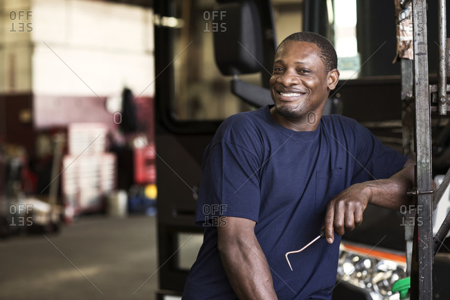 Bus mechanic smiling in garage