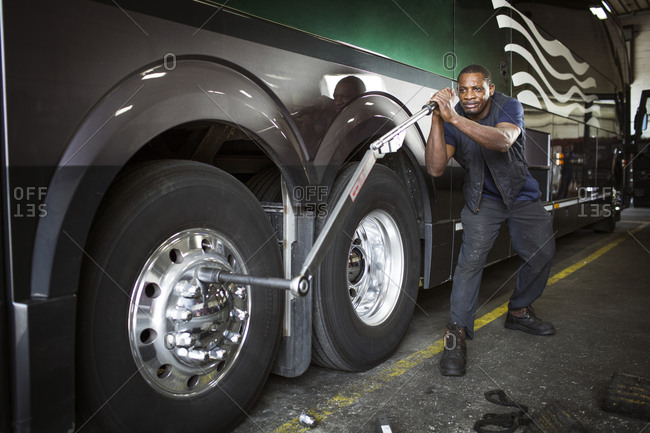 Bus mechanic using wrench to unscrew tire bolts