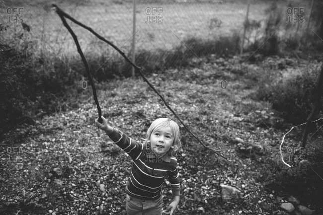 Boy playing with a stick in the garden