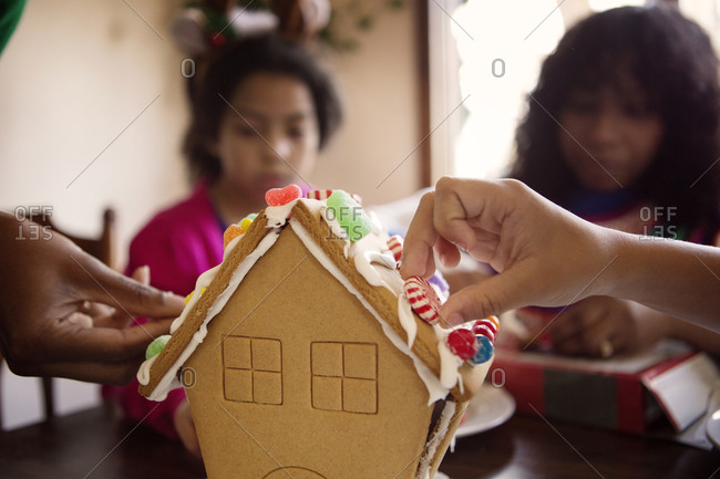 Family decorating a gingerbread house with candy
