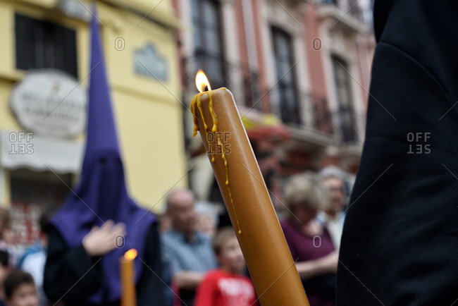 Penitents holding candles at a procession during Holy Week in Granada, Spain
