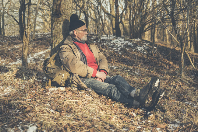 Old man resting on the ground in a forest