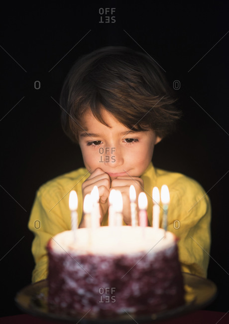 Portrait of boy thinking of birthday wishes, Looking at birthday cake