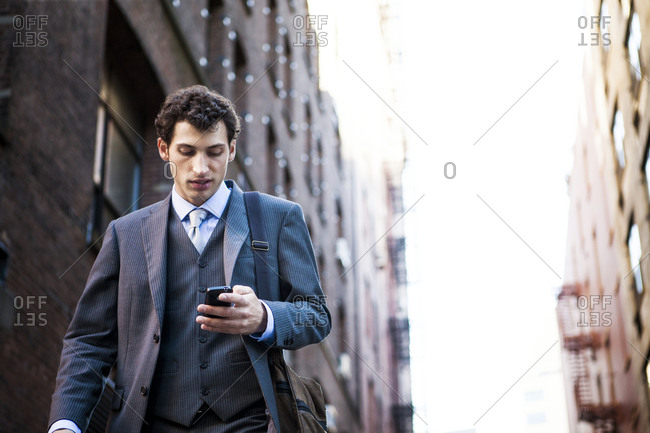 A man walks down the street while checking his cell phone