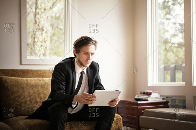 Man in suit on couch using a tablet