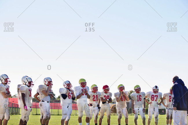 A high school football team gathers around their coach