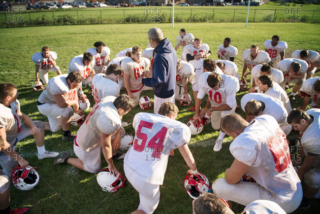 A high school football team gathers around the coach