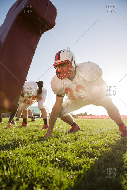 High school football players prepare to charge a tackling dummy