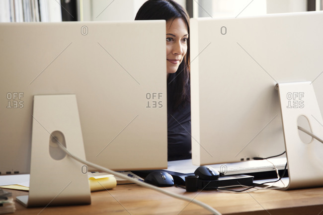 A woman works with two monitors
