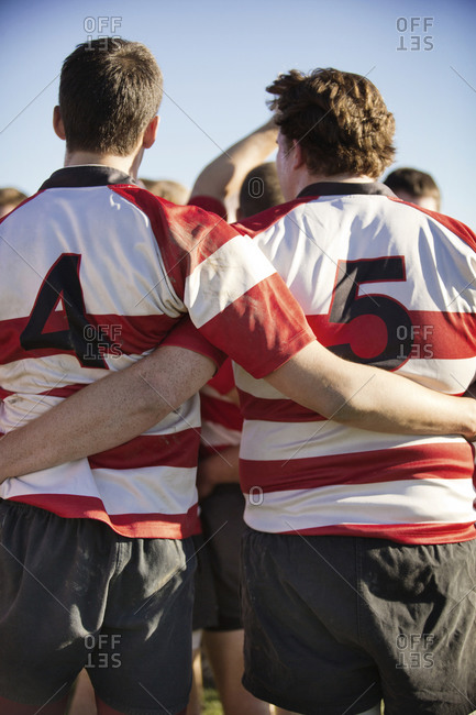 Back view of rugby teammates with arms around each other