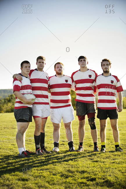 Portrait of five rugby players standing with arms around each other
