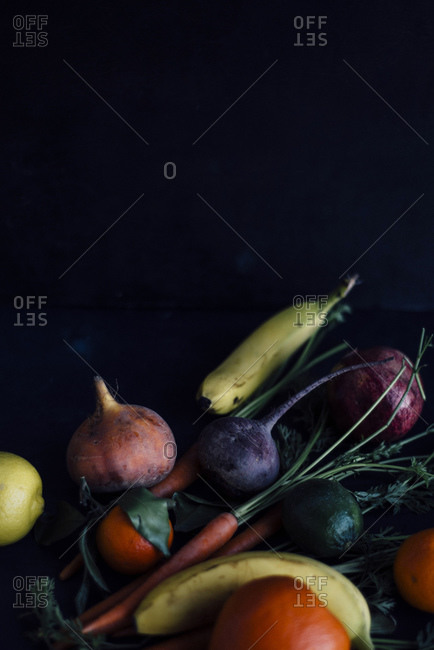 Several fruits and root vegetables on dark background
