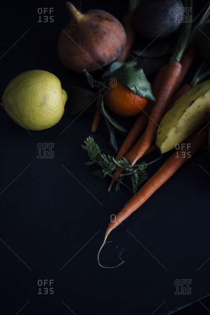 Various fruits and root vegetables on dark background