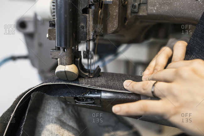 Close-up of sewing seam with denim at industrial machine