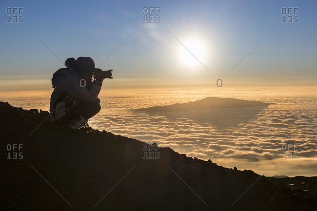A woman photographing Hualalai peaks from Mauna Kea on the Big Island of Hawaii