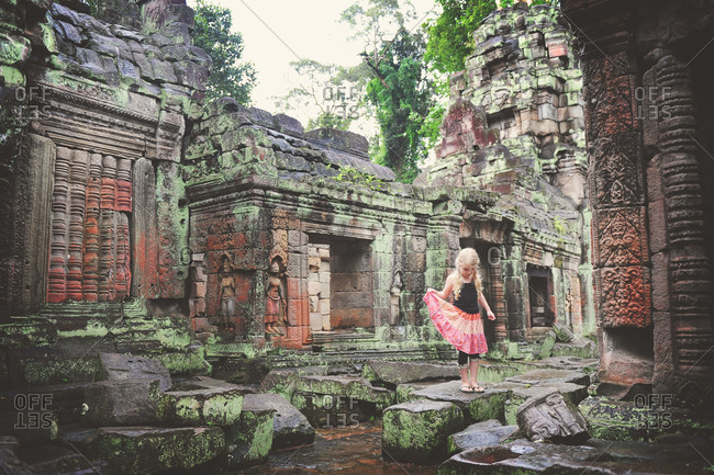 A young girl walking on stones of ancient temple ruins, Cambodia