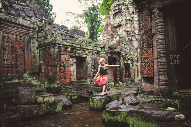 Young girl playing on the stones of an ancient temple in Cambodia