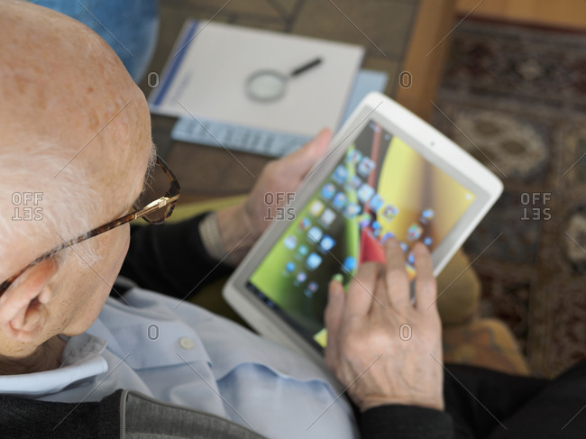 Old man at home using digital tablet