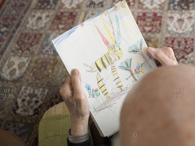 Old man at home looking at child\'s drawing