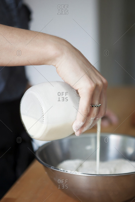 Close up of woman adding milk to a flour mixture