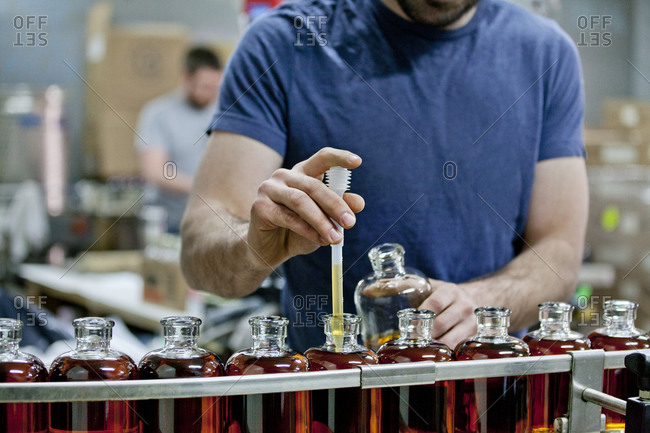 A distillery worker collects a sample of whiskey