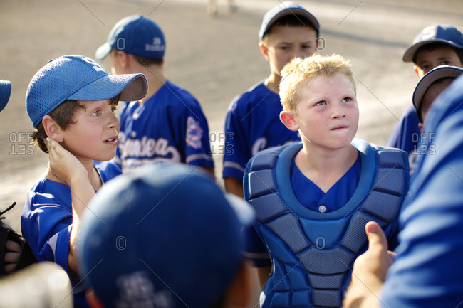 A little league baseball team gathers around their coach