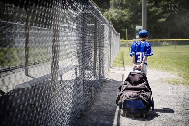 A little league player drags supplies off the field