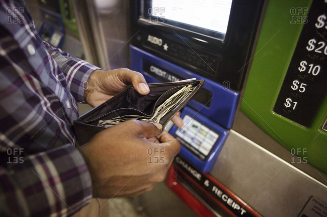 Man getting money out of wallet at transit card machine
