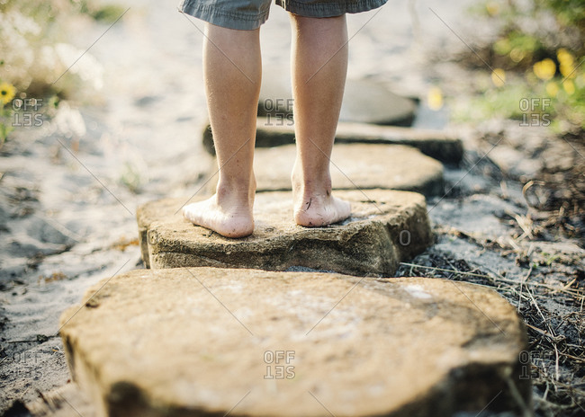 Feet of boy standing on stones along path