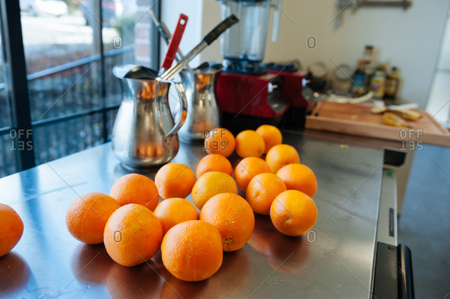 Oranges laid out for peeling and juicing on a stainless steel counter at a juice bar